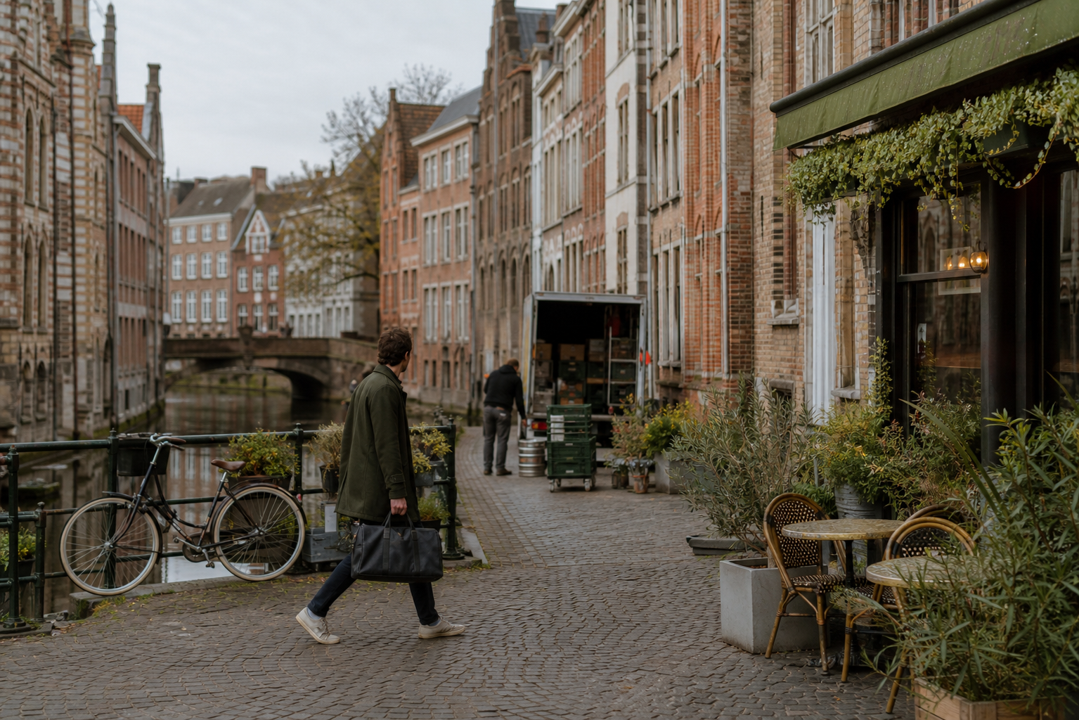 Reiziger loopt met een weekendtas langs een Gents kanaal en bakstenen gevels